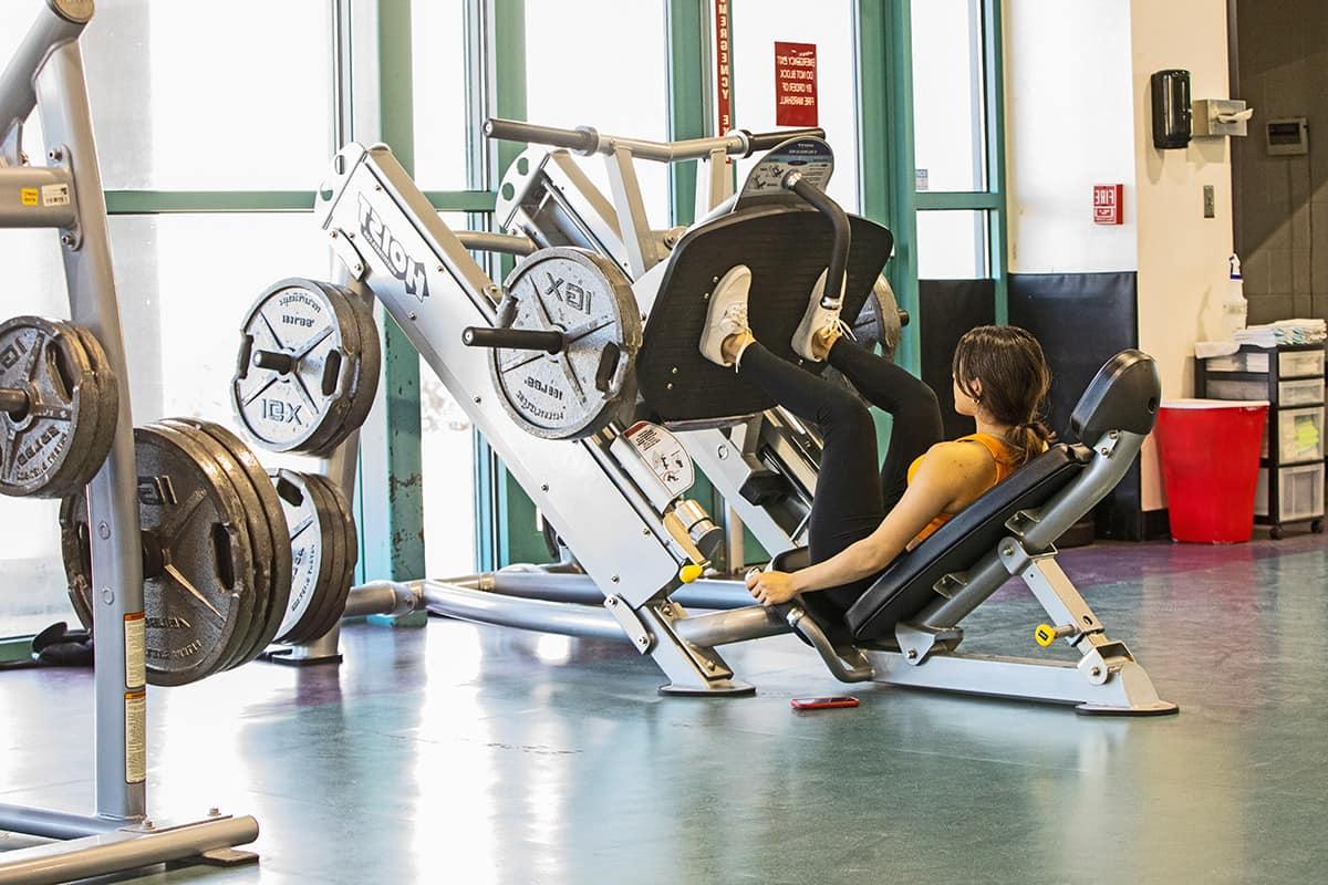 Female student works out with leg press in hhpc.